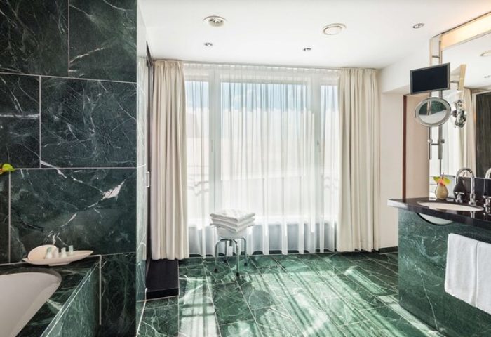 Grand Hyatt Berlin gay-friendly hotel bathroom. Green marble, white towels, and bright window. A luxurious experience for gay travelers.