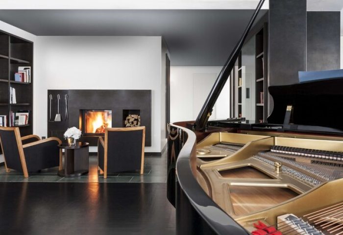 Grand Hyatt Berlin gay-friendly hotel suite with piano, fireplace, and lounge chairs. Upscale gay travel in Berlin. Luxury hotel room.
