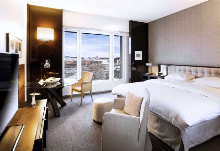 Grand Hyatt Berlin gay-friendly hotel room. Modern design with a bed, chairs, and a view of the city. Luxury travel for gay men in Berlin.