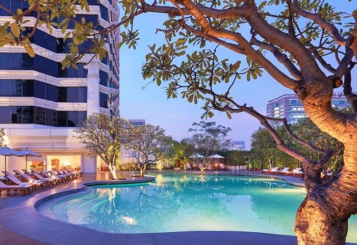 Grand Hyatt Erawan Bangkok gay-friendly hotel pool. Relaxing pool area with deck chairs and trees. Perfect for gay travelers in Bangkok.