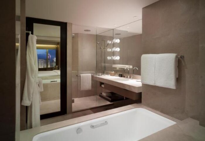 Grand Hyatt Hong Kong gay-friendly hotel bathroom. Modern design with bathtub, shower, and cityscape view. Ideal for gay men travel in Hong Kong.