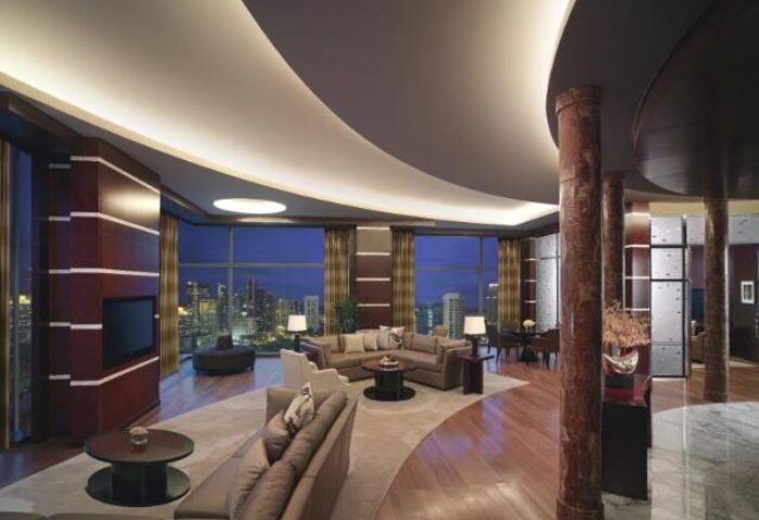 Grand Hyatt Kuala Lumpur Hotel suite. Gay-friendly hotel with city view at night. Luxury interior with sofas, TV, and marble columns.