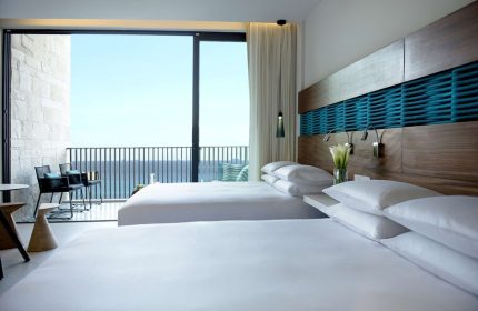 Grand Hyatt Playa Del Carmen Resort gay-friendly hotel room. Ocean view from balcony. Two beds with white linens and pillows. Modern design.