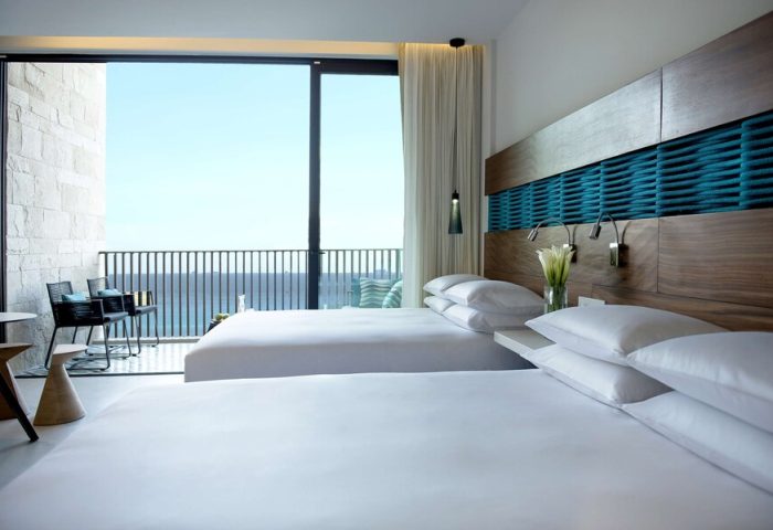 Grand Hyatt Playa Del Carmen Resort gay-friendly hotel room. Ocean view from balcony. Two beds with white linens and pillows. Modern design.