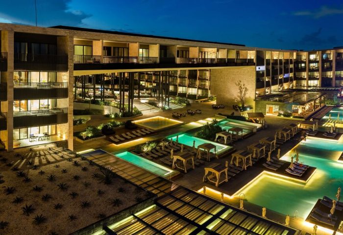 Grand Hyatt Playa Del Carmen Resort at night. Gay-friendly hotel with pools, lounge chairs, and modern architecture. Luxury travel destination.