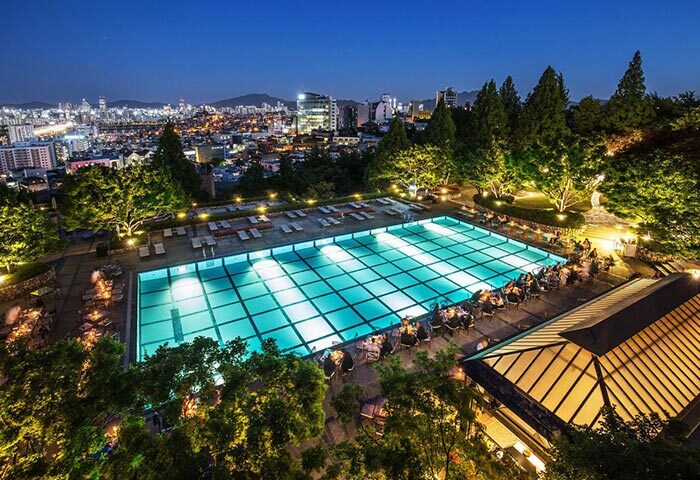 Grand Hyatt Seoul gay-friendly hotel pool at night. Illuminated pool with city skyline. Upscale travel destination for gay men.