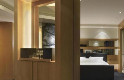 Grand Hyatt Seoul gay-friendly hotel room. View of the bed and a wooden cabinet with glasses. Luxury travel for gay men in Seoul.