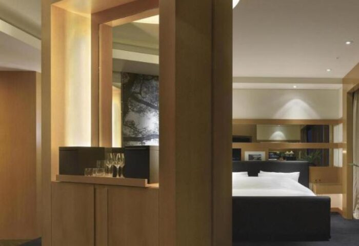 Grand Hyatt Seoul gay-friendly hotel room. View of the bed and a wooden cabinet with glasses. Luxury travel for gay men in Seoul.
