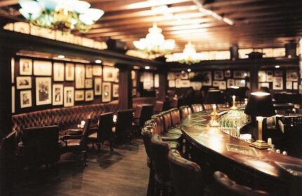 Grand Hyatt Seoul's bar, a gay-friendly hotel. Dark wood bar, leather chairs, framed photos, and chandeliers create a sophisticated ambiance.