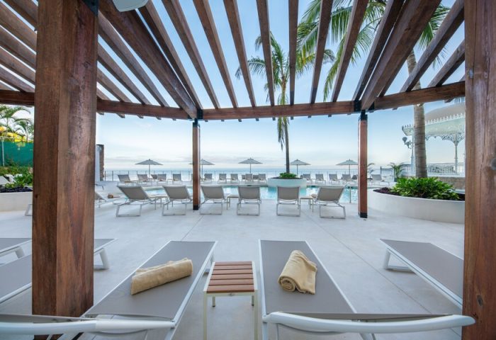 Poolside view at Grand Park Royal Puerto Vallarta, a gay-friendly all-inclusive hotel. Lounge chairs, umbrellas, and ocean views. Relaxing vacation.