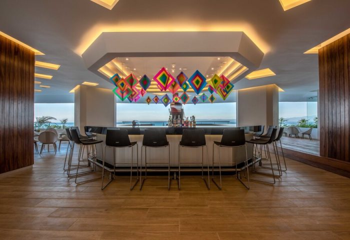 Bar at Grand Park Royal Puerto Vallarta All-Inclusive, a gay-friendly hotel. Colorful diamond decorations hang above the bar with ocean view.