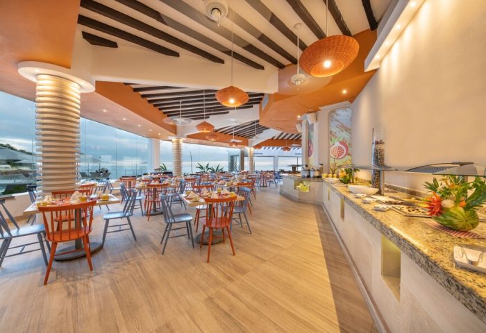 Dining area at Grand Park Royal Puerto Vallarta All Inclusive, a gay-friendly hotel. Tables are set, buffet line visible. Ocean view.
