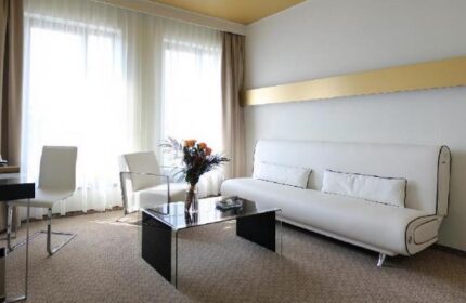 Grandior Hotel Prague room. Modern interior with white sofa, chairs, and glass table. Gay-friendly hotel for gay men's travel advice.