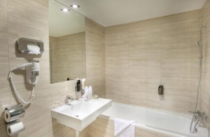 Grandior Hotel Prague bathroom. Gay-friendly hotel features modern fixtures, a bathtub, sink, and hair dryer. Ideal for gay travel in Prague.