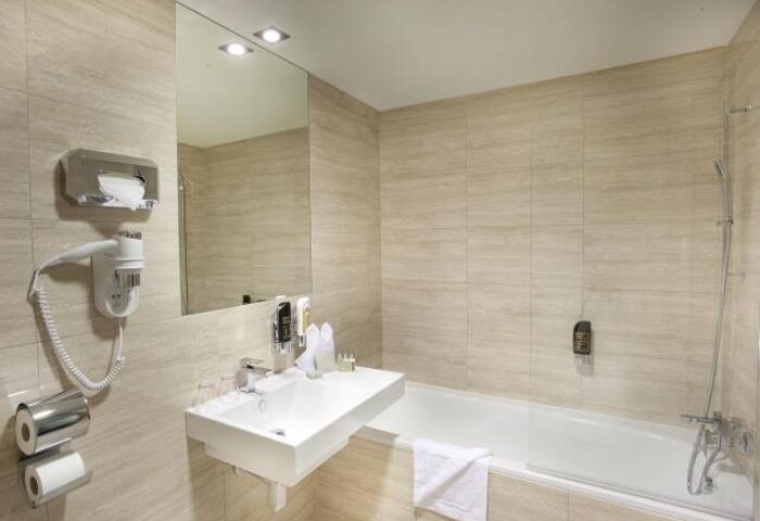 Grandior Hotel Prague bathroom. Gay-friendly hotel features modern fixtures, a bathtub, sink, and hair dryer. Ideal for gay travel in Prague.