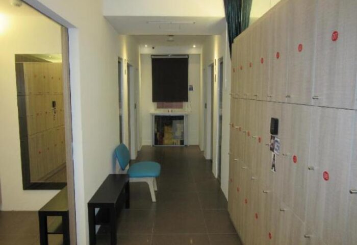 Hallway at Gs Gay Hotel, a gay-friendly hotel. Lockers line the wall. A bench and chair offer seating. Interior design for gay men's travel.