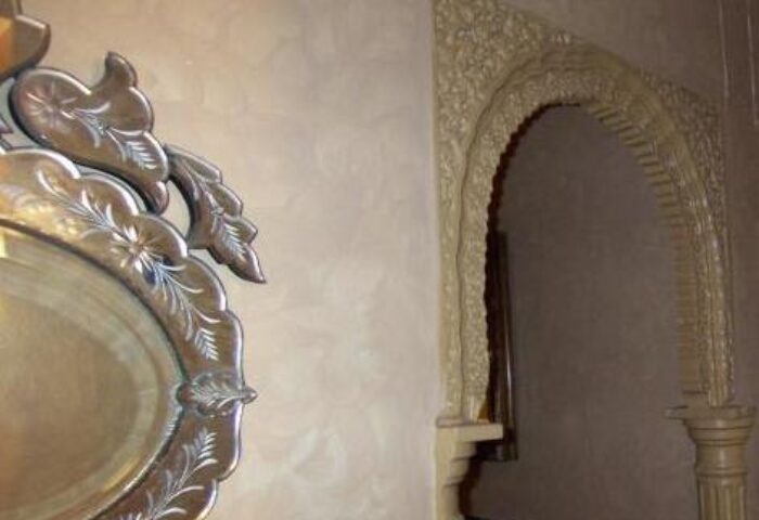 Guadalupe Cozy Inns' gay-friendly hotel interior. A decorative mirror and Moorish archway add charm. Travel advice for gay men seeking unique stays.
