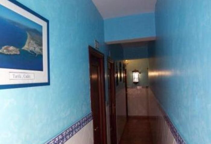 Hallway at Guadalupe Cozy Inns, a gay-friendly hotel. Blue walls, tile accents, & framed art create a welcoming space for gay travelers.