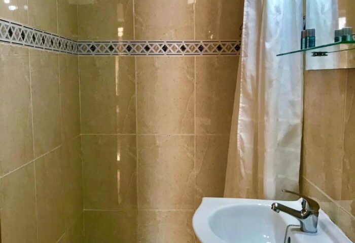Bathroom at Guadalupe Cozy Inns, a gay-friendly hotel. Features a shower, sink, and tiled walls for a comfortable stay.