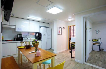 Guest House DODAMi's communal kitchen. Gay-friendly hotel with a dining table, white cabinets, and modern appliances. A welcoming space for gay travelers.