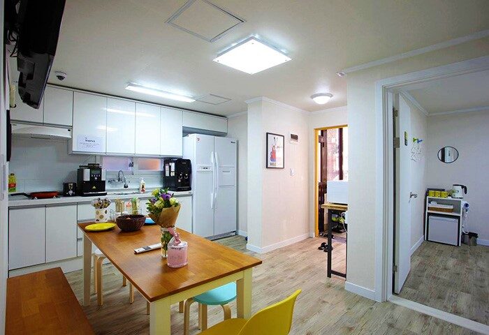 Guest House DODAMi's communal kitchen. Gay-friendly hotel with a dining table, white cabinets, and modern appliances. A welcoming space for gay travelers.