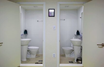 Guest House DODAMi bathroom. Gay-friendly hotel featuring two bathrooms with white tile, toilet, and sink. Travel advice for gay men.