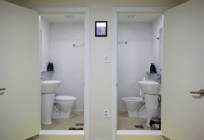 Guest House DODAMi bathroom. Gay-friendly hotel featuring two bathrooms with white tile, toilet, and sink. Travel advice for gay men.