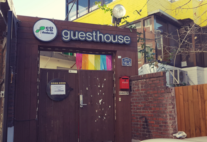 Entrance to Guest House DODAMi, a gay-friendly hotel. The guesthouse has a wooden gate and a rainbow decoration. Gay travel advice.