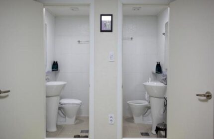 Guest House DODAMi: Two open bathroom doors. Gay-friendly hotel with white tile, pedestal sinks, and toilets. Ideal for gay men travel.