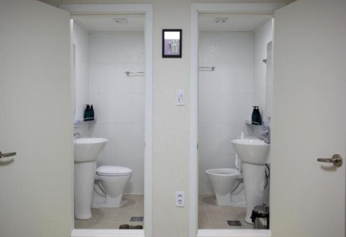 Guest House DODAMi: Two open bathroom doors. Gay-friendly hotel with white tile, pedestal sinks, and toilets. Ideal for gay men travel.