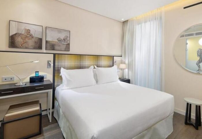 H10 Art Gallery Hotel bedroom. Gay-friendly hotel room with white linens, desk, and modern art. Comfortable stay for gay travelers.