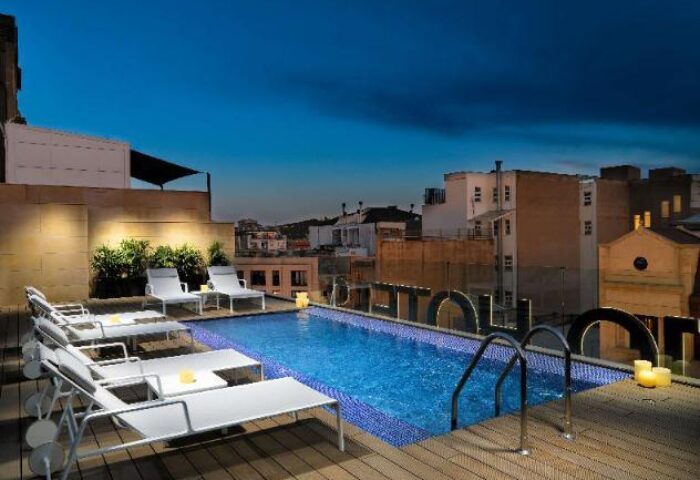 Rooftop pool at the gay-friendly H10 Art Gallery Hotel. Lounge chairs line the pool deck, offering a relaxing space in this Barcelona hotel.