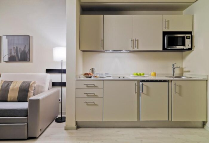 H10 Berlin Ku'damm Hotel kitchenette. Gay-friendly hotel room with microwave, sink, and sofa. Ideal for gay travelers in Berlin.