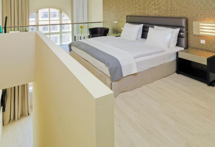 H10 Berlin Ku'damm Hotel room. Gay-friendly hotel with modern design. Kudamm hotel bedroom with bed, window, and stylish decor.