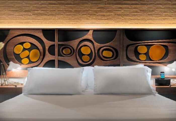 H10 Metropolitan Hotel bedroom. Gay-friendly hotel room featuring a bed with white linens and a decorative headboard with yellow accents.
