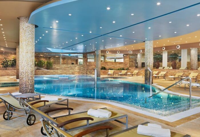 Indoor pool at Gay-Friendly H10 Playa Meloneras Palace. Relaxing space with loungers, blue ceiling, and mosaic details. Ideal for gay travel.