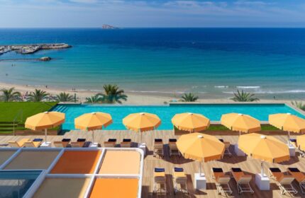 H10 Porto Poniente 4* Sup gay-friendly hotel pool view. Benidorm beach, sun umbrellas, and loungers. Perfect for gay travel advice.
