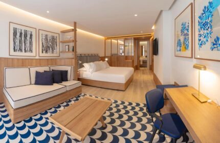 H10 Porto Poniente 4* Sup gay-friendly hotel room. Modern design with bed, sofa, desk, and blue/white patterned rug. Stylish Benidorm stay.