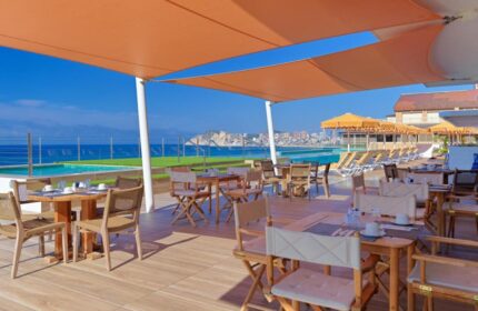 H10 Porto Poniente 4* Sup gay-friendly hotel's outdoor dining area with sea view. Tables and chairs under a sunshade near the pool.