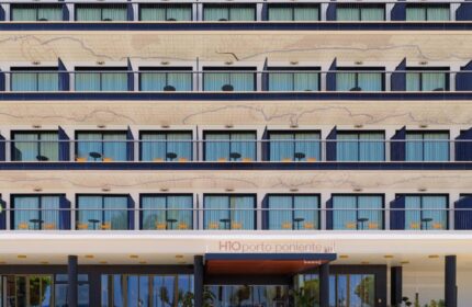 H10 Porto Poniente 4* Sup gay-friendly hotel facade. Modern design, balconies, and entrance with yellow benches. Gay travel in Benidorm.