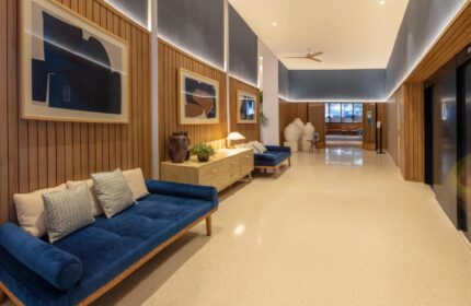 H10 Porto Poniente 4* Sup gay-friendly hotel lobby. Blue sofas, wood paneling, and modern art create a stylish, welcoming space.