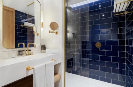H10 Porto Poniente 4* Sup gay-friendly hotel bathroom. Blue tiled shower, gold fixtures, and modern design. Ideal for gay travel.