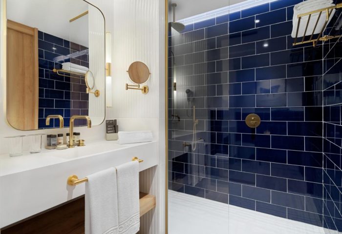 H10 Porto Poniente 4* Sup gay-friendly hotel bathroom. Blue tiled shower, gold fixtures, and modern design. Ideal for gay travel.