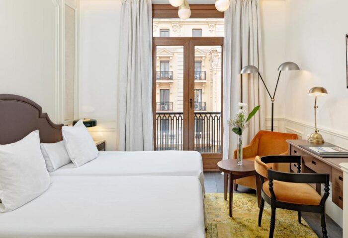 H10 Villa de la Reina Boutique Hotel room. Gay-friendly hotel with twin beds, balcony, desk, and seating area. Great for gay travel in Madrid.