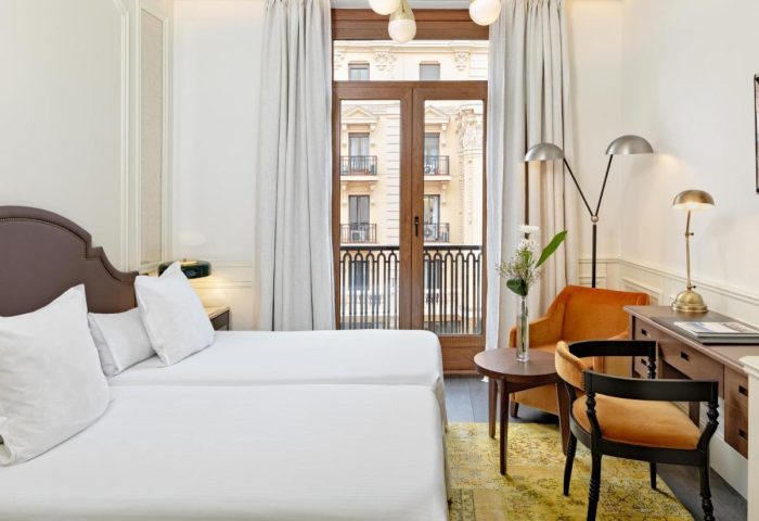 H10 Villa de la Reina Boutique Hotel room. Gay-friendly hotel with twin beds, balcony, desk, and seating area. Great for gay travel in Madrid.