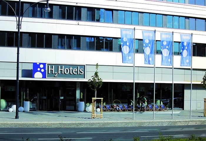Exterior of H2 Hotel Berlin-Alexanderplatz, a gay-friendly hotel. Flags and a modern facade welcome guests to this popular Berlin hotel.