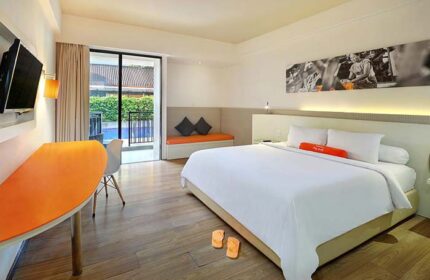 Bright room at gay-friendly HARRIS Hotel Seminyak. King bed, orange accents, pool view. Modern, clean design. Ideal for gay travel in Seminyak.