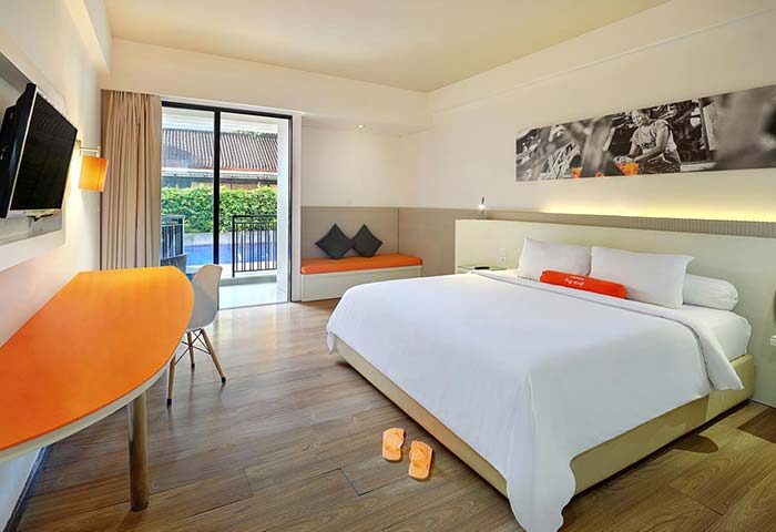 Bright room at gay-friendly HARRIS Hotel Seminyak. King bed, orange accents, pool view. Modern, clean design. Ideal for gay travel in Seminyak.