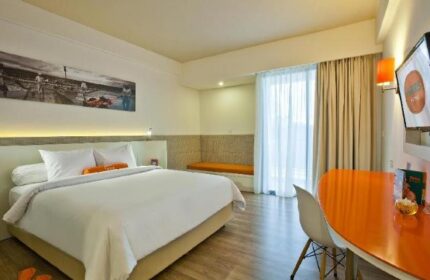 HARRIS Hotel Seminyak room. Gay-friendly hotel bedroom with white linens, orange accents, desk, and TV. Modern design for gay travelers.