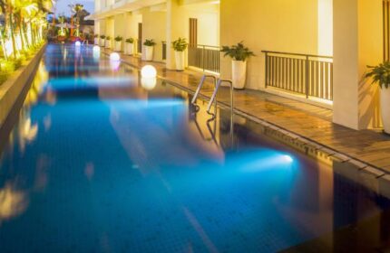 HARRIS Hotel Seminyak pool at dusk. Gay-friendly hotel with modern design, blue-lit pool, and poolside plants. Ideal for gay travel in Seminyak.